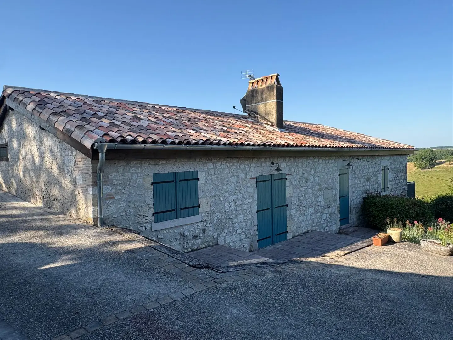 Ferme en pierre avec toiture rénovée, volets verts et oliviers